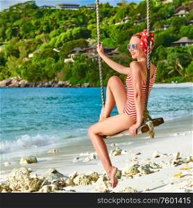 Woman swinging at tropical beach, Petite Anse, Mahe, Seychelles.