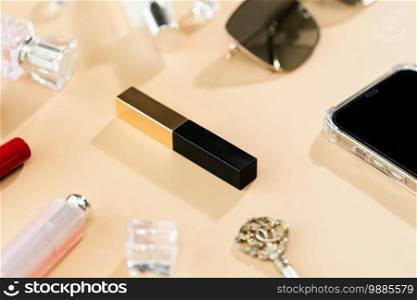 woman table desk frame. cosmetics, lipstick, perfume, phone and sunglasses on yellow background.