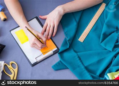Woman tailor working on a clothing sewing stitching measuring fa. Woman tailor working on a clothing sewing stitching measuring fabric