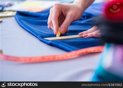 Woman tailor working on a clothing sewing stitching measuring fa. Woman tailor working on a clothing sewing stitching measuring fabric