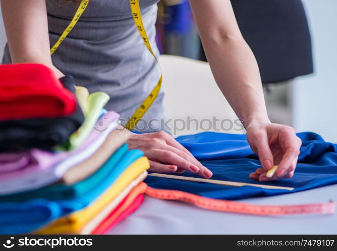 Woman tailor working on a clothing sewing stitching measuring fabric. Woman tailor working on a clothing sewing stitching measuring fa