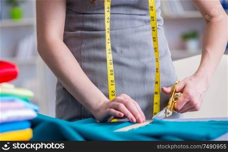 Woman tailor working on a clothing sewing stitching measuring fabric. Woman tailor working on a clothing sewing stitching measuring fa