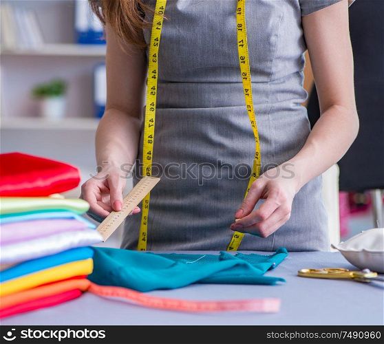 Woman tailor working on a clothing sewing stitching measuring fabric. Woman tailor working on a clothing sewing stitching measuring fa