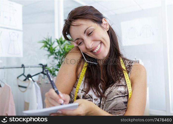 woman tailor working on sketches on the phone