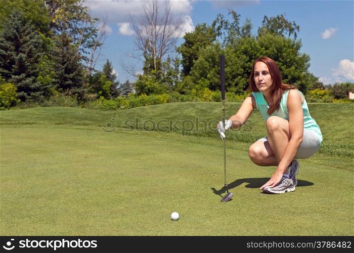 Woman takes aim for her putt on the golf green