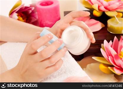 Woman takes care about her nails and putting cream on her hands