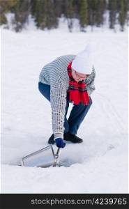 Woman taking a household water from a ice hole.