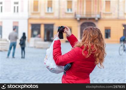 Woman taking a photo in the street. Real people. Unrecognizeable