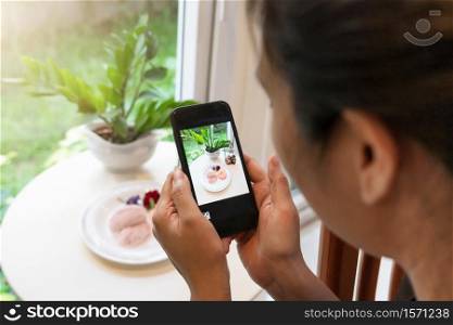 Woman taking a photo of dessert with smartphone