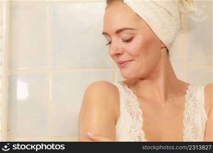 Woman taking care of her dry skin applying moisturizer cream lotion on her body in bathroom. Skincare spa treatment.. Woman applying moisturizer cream on her body