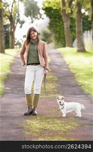 Woman Taking Dog For Walk Outdoors In Autumn Park