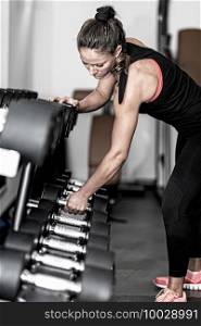 Woman taking dumbbell and starting with weight training in health club