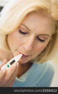 Woman Taking Her Temperature With Thermometer