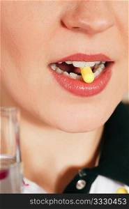 Woman taking in a pharmaceutical pill (close up on mouth) for medicine, health concept
