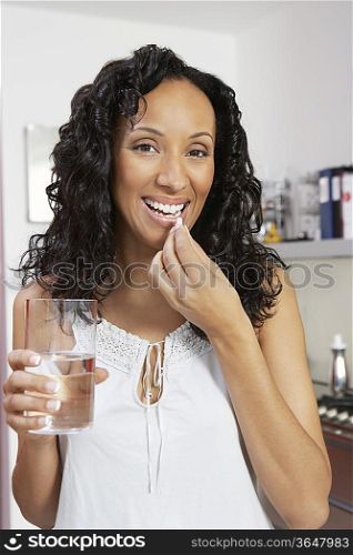 Woman taking medication, smiling, indoors, portrait