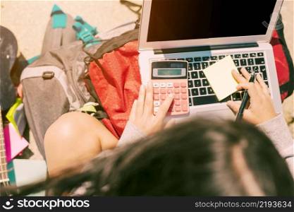 woman taking notes by hand with calculator laptop sunny day