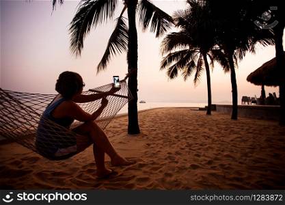 woman taking photo by smart phone at dawn