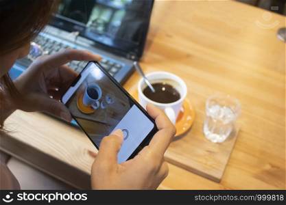 Woman taking photo on coffee in cafe