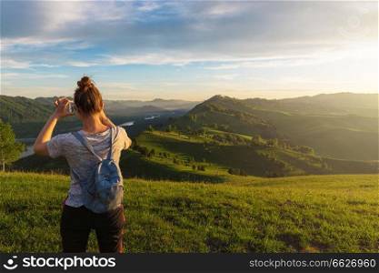 Woman taking photo on mobile phone at the mountain peak.. Woman taking photo in mountain