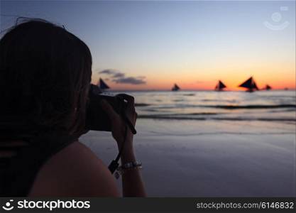 Woman taking photographs of yachts. Woman taking photographs of yachts sailing in tropical sea at sunset