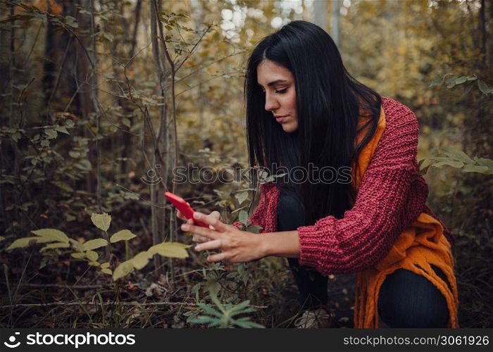 Woman taking photos with her phone through the forest