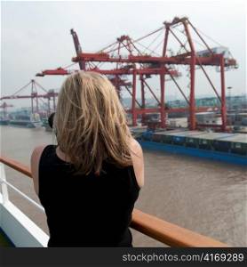 Woman taking picture of commercial dock, Yangtze River, Shanghai, China