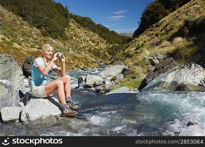 Woman taking picture of river in forest