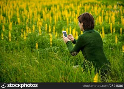 Woman taking pictures to flowers with a cellphone