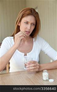 Woman taking pills to ease headache