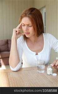 Woman taking pills to ease headache