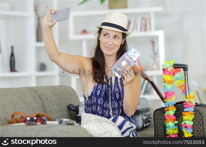woman taking selfie of herself holding passports and travel tickets