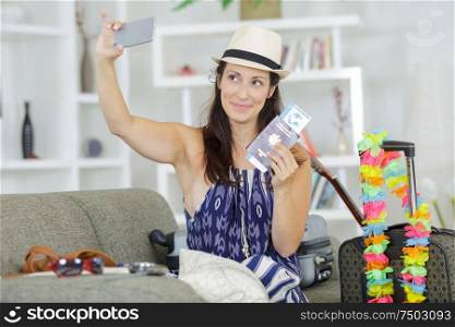 woman taking selfie of herself holding passports and travel tickets