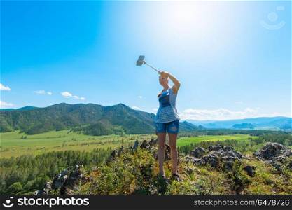 Woman taking selfie on mobile phone. Woman taking selfie on mobile phone with stick. Vacation in the mountain