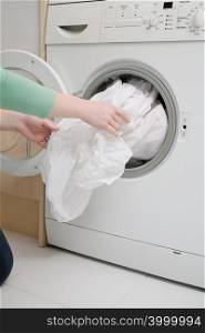 Woman taking sheet from washing machine