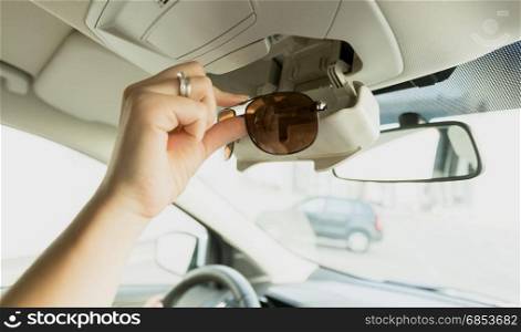 Woman taking sunglasses out of special car compartment
