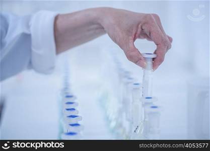 Woman taking test tube from row of test tubes, close-up
