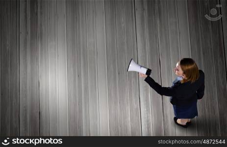 Woman talking in bullhorn. Top view of businesswoman with megaphone in hand