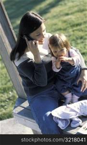 Woman Talking on Cell Phone Holding Baby