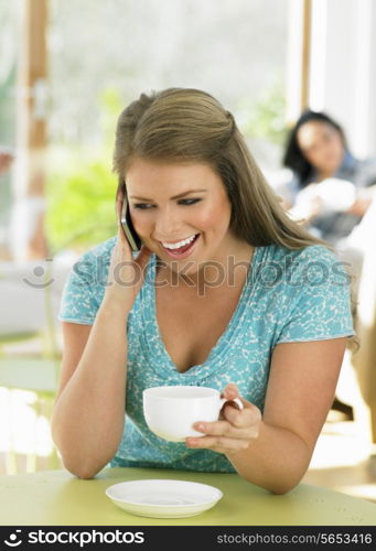 Woman Talking On Mobile Phone In Cafe