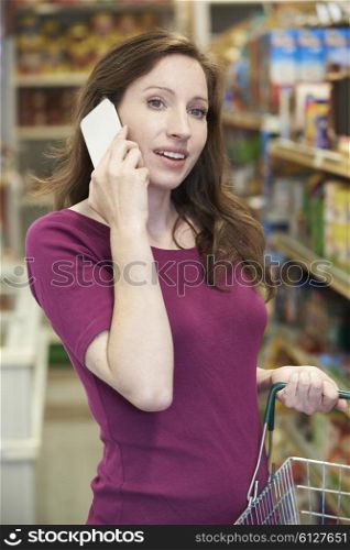 Woman Talking On Mobile Phone In Supermarket