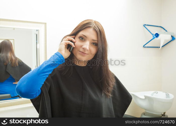 Woman talking on phone ar hairdresser salon, waiting to get done hair.. Woman talking on phone ar hairdresser salon