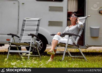 Woman talking on smart phone outdoors in a campsite for holidaymakers. Caravan car Vacation. Family vacation travel, holiday trip in motorhome RV. Connection information communication technology.