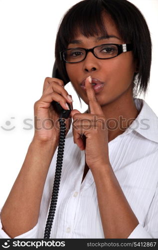 Woman talking on the phone and holding her finger to her lips