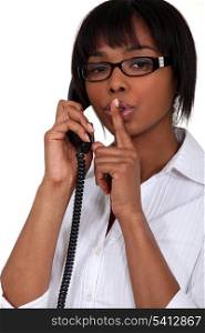 Woman talking on the phone and holding her finger to her lips