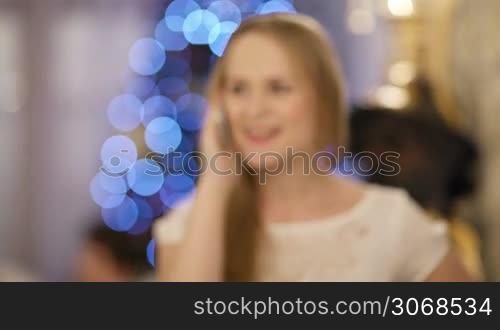Woman talking on the phone during Christmas celebration. X-mas greetings.