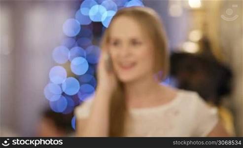 Woman talking on the phone during Christmas celebration. X-mas greetings.