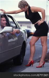 Woman talking to a man in a car
