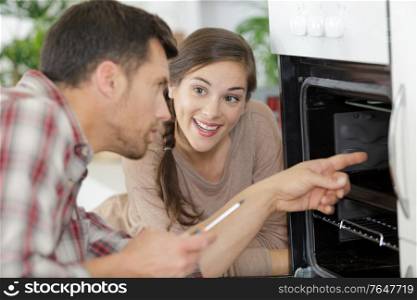 woman talking to male worker repairing inside the oven