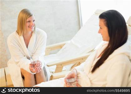 Woman talking with friend while having water at beauty spa