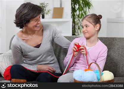 Woman teaching her granddaughter how to knit